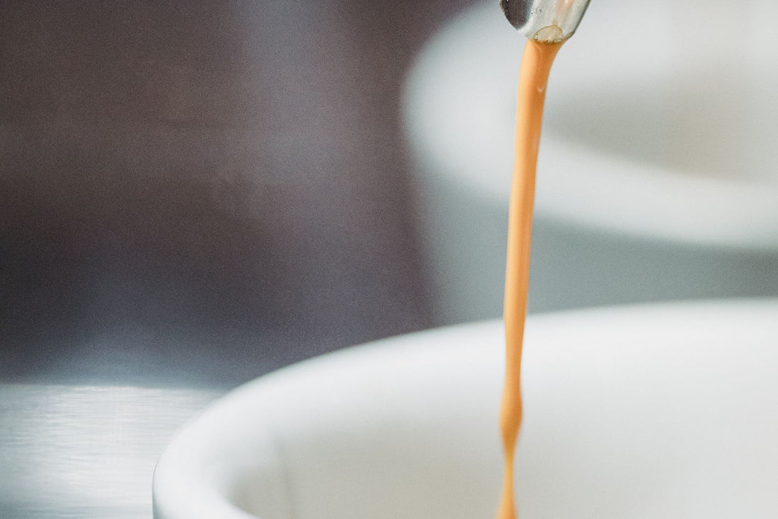 Espresso pouring into a white cup with rich crema