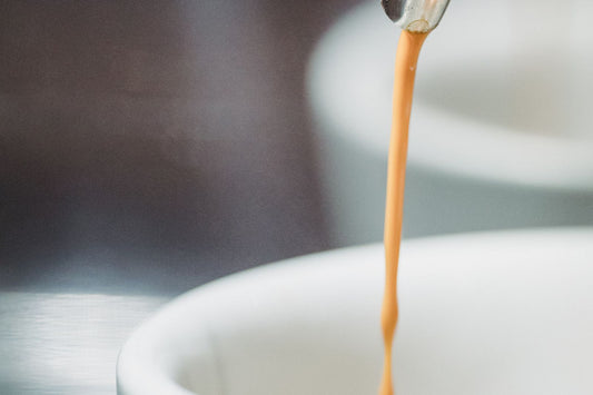 Espresso pouring into a white cup with rich crema