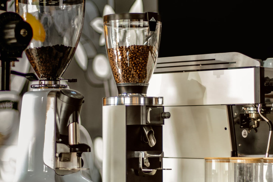 Burr coffee grinders with beans in the hoppers beside an espresso machine