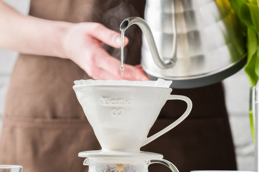 Hot water poured from a gooseneck kettle into a V60 pour-over dripper