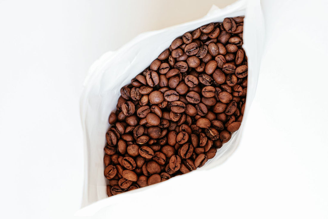 Whole roasted coffee beans inside an open foil coffee bag